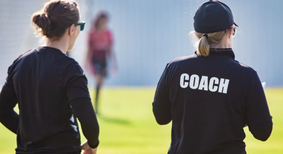 twee personen op een voetbalveld met één coach